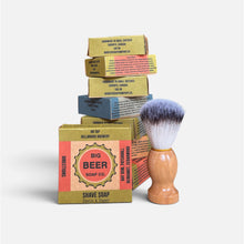 A wooden-handled shaving brush  in front of stacked Big Beer Soap Co. boxes  